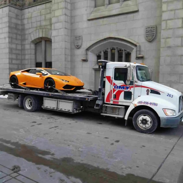 Metro FB-10 rollback flatbed transporting a Lamborghini supercar in city streets