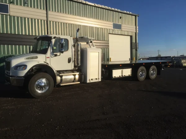 Metro FB-15 flatbed tow truck in white color parked by warehouse building