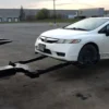 Metro FB-15 flatbed tow truck using wheel lift to tow a white sedan
