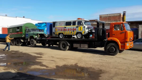 Metro FB-15 flatbed hauling a van and a truck in an industrial yard