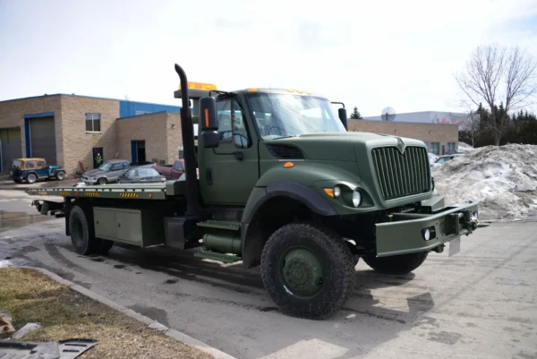 Metro FB-15 military-green flatbed tow truck with heavy-duty chassis parked outdoors