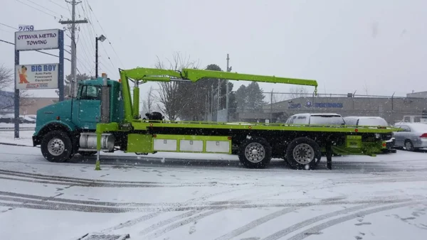 Metro FB-20 flatbed tow truck side view in snowy parking lot