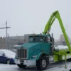 Metro FB-20 flatbed tow truck with knuckle crane extending and outriggers deploying in winter conditions
