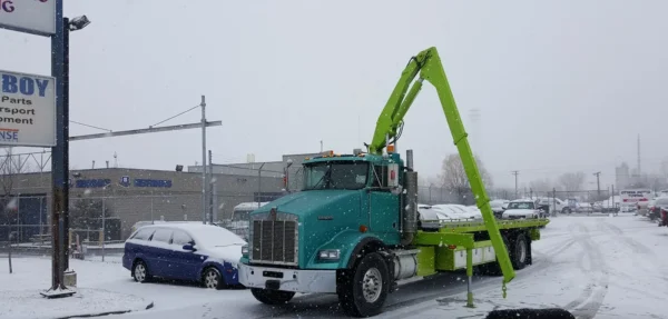 Metro FB-20 flatbed tow truck with knuckle crane extending and outriggers deploying in winter conditions