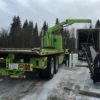 Metro FB-20 flatbed truck unloading steel structure from trailer using rear crane in snowy construction yard
