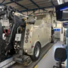 Metro Tow Trucks INT-16 beige heavy-duty integrated wrecker rear side view during maintenance inside workshop
