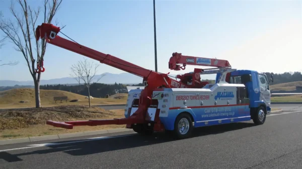 Metro Tow Trucks INT-16 blue and white heavy-duty integrated wrecker rear view with extended red boom and underlift in open field
