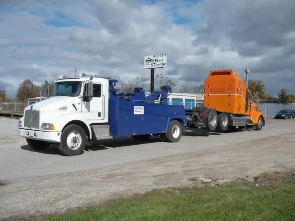 Metro Tow Trucks INT-16 blue and white heavy-duty integrated wrecker towing orange truck on roadside
