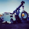 Metro Tow Trucks INT-16 white heavy-duty integrated wrecker lifting large industrial steel coil during recovery operation