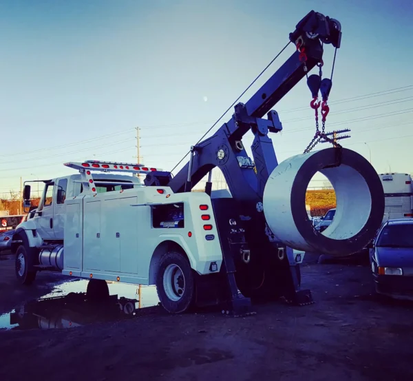 Metro Tow Trucks INT-16 white heavy-duty integrated wrecker lifting large industrial steel coil during recovery operation
