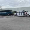 Metro Tow Trucks INT-16 white heavy-duty integrated wrecker towing a bus in industrial parking lot