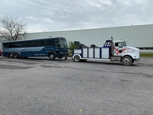 Metro Tow Trucks INT-16 white heavy-duty integrated wrecker towing a bus in industrial parking lot