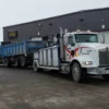 Metro Tow Trucks INT-16 white heavy-duty integrated wrecker towing heavy dump truck at customer site