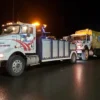 Metro Tow Trucks INT-16 white heavy-duty integrated wrecker towing a dump truck at night with warning lights on