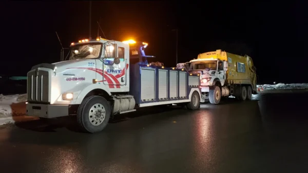 Metro Tow Trucks INT-16 white heavy-duty integrated wrecker towing a dump truck at night with warning lights on