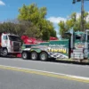Green INT-35 heavy-duty integrated wrecker towing a large trailer on public roadway with highway traffic
