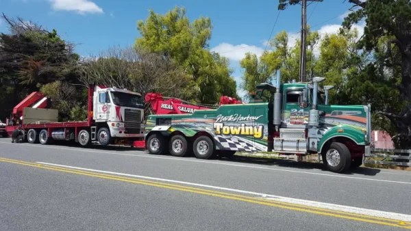 Green INT-35 heavy-duty integrated wrecker towing a large trailer on public roadway with highway traffic