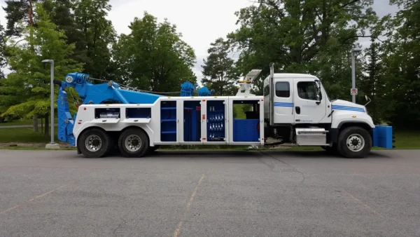 White INT-35 integrated wrecker with blue boom and multiple equipment compartments open for display