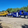 Blue INT-35 heavy-duty wrecker transporting a school bus
