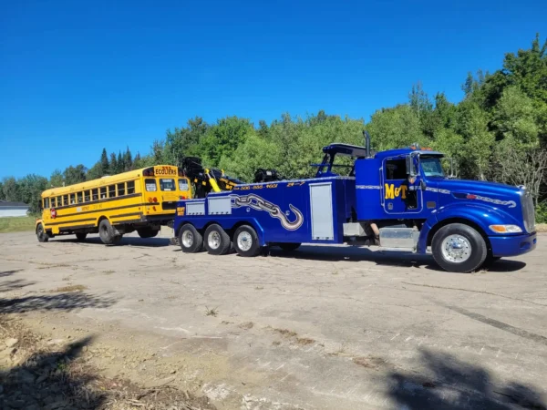 Blue INT-35 heavy-duty wrecker transporting a school bus