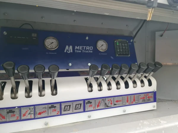 Integrated hydraulic control panel inside INT-35 wrecker equipment cabinet with labeled levers