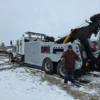 White INT-35 wrecker parked in snowy yard with boom raised and the customer standing beside unit