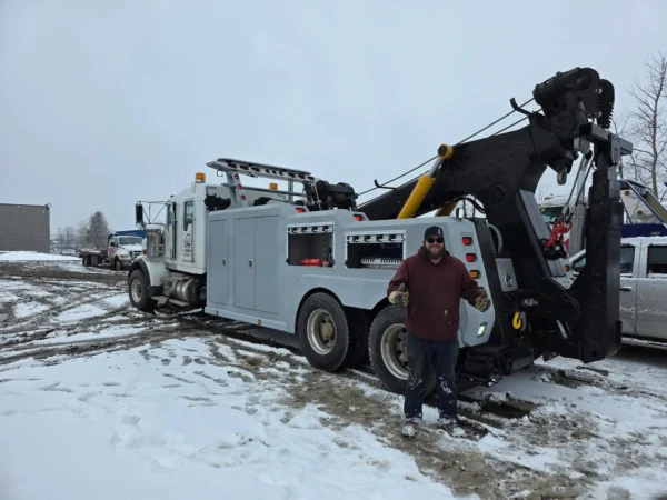 White INT-35 wrecker parked in snowy yard with boom raised and the customer standing beside unit
