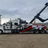Black and white INT-35 heavy-duty integrated wrecker with recovery boom extended in industrial lot