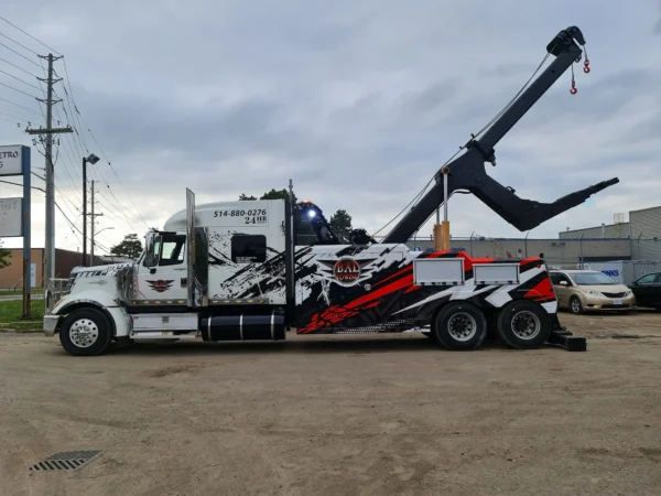 Black and white INT-35 heavy-duty integrated wrecker with recovery boom extended in industrial lot