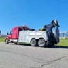 Red and gray INT-35 integrated wrecker extending boom during roadside recovery operation