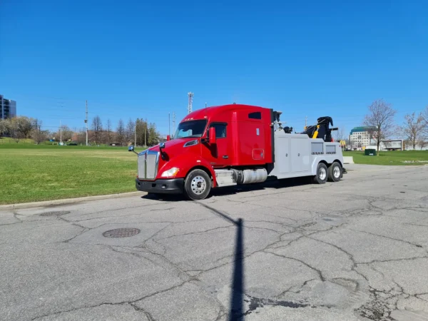 Red and grey INT-35 integrated wrecker driving on paved road with boom