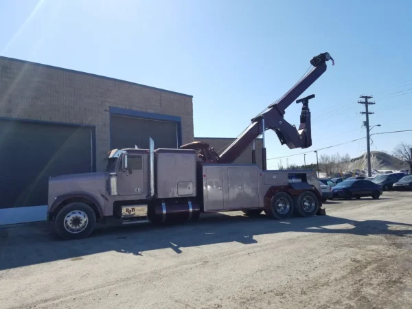 INT-35 heavy-duty integrated wrecker with extended recovery boom parked beside industrial building