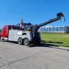 Red and gray INT-35 integrated wrecker extending boom during recovery demonstration on open roadway
