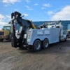 Grey INT-35 heavy-duty integrated wrecker parked in yard with boom stowed and dual rear axles visible