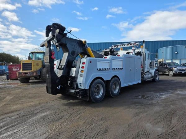 Grey INT-35 heavy-duty integrated wrecker parked in yard with boom stowed and dual rear axles visible