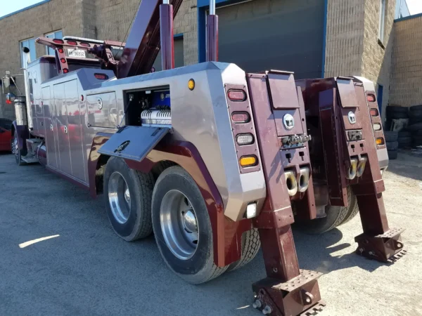 Rear view of INT-35 wrecker showing dual hydraulic outriggers and underlift controls