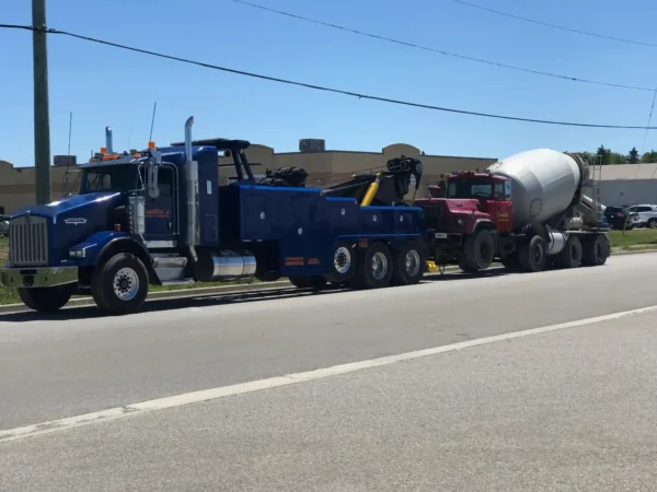 INT-60 heavy duty integrated wrecker towing a cement mixer truck on a major roadway during recovery transport