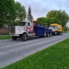 INT-60 heavy duty integrated wrecker towing a garbage truck along a rural roadway