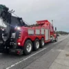 INT-60 integrated heavy wrecker in red towing configuration with boom and underlift on major roadway