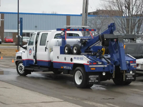 White and blue Metro INT-5 tow truck side view in parking area