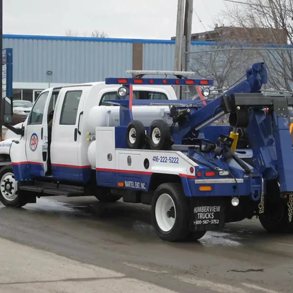 White and blue Metro INT-5 tow truck side view in parking area