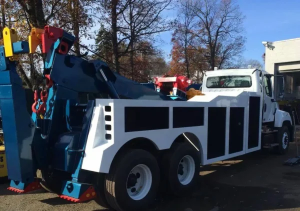 Finished Integrated INT-30 heavy duty wrecker with body painted white and boom painted blue, parked outdoors