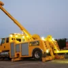 Metro RTR-16 rotator wrecker illuminated for nighttime heavy recovery mission with boom raised and extended