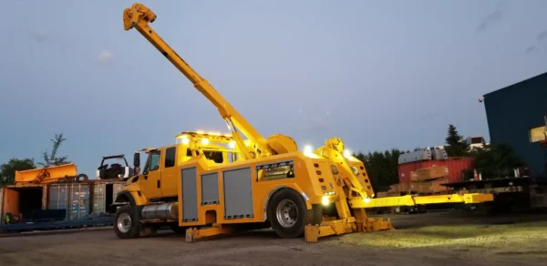 Metro RTR-16 rotator wrecker illuminated for nighttime heavy recovery mission with boom raised and extended