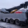 Metro Tow Trucks RTR-50 rotator with boom lowered and support equipment in snowy recovery yard