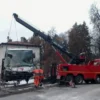 Metro RTR-70 70-ton rotator lifting a damaged vehicle near residential property