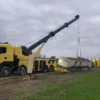 Metro RTR-70 rotator recovering a rolled-over semi-truck and trailer in roadside field