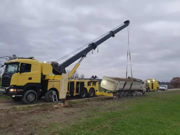 Metro RTR-70 rotator recovering a rolled-over semi-truck and trailer in roadside field