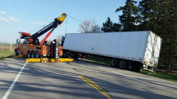Metro RTR-70 heavy-duty rotator recovering a semi-truck trailer with a container on highway