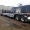 Tri-axle TSA-50 heavy-duty equipment trailer with full-length flat deck, parked at yard